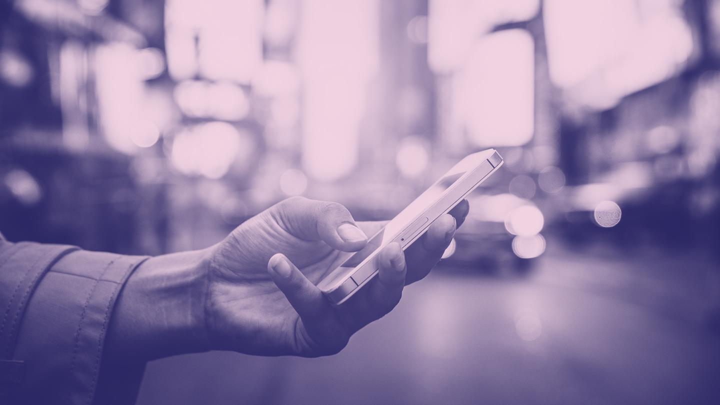 Colorized photo of a person's hand holding a smartphone in an urban setting, featured in Finding the way forward